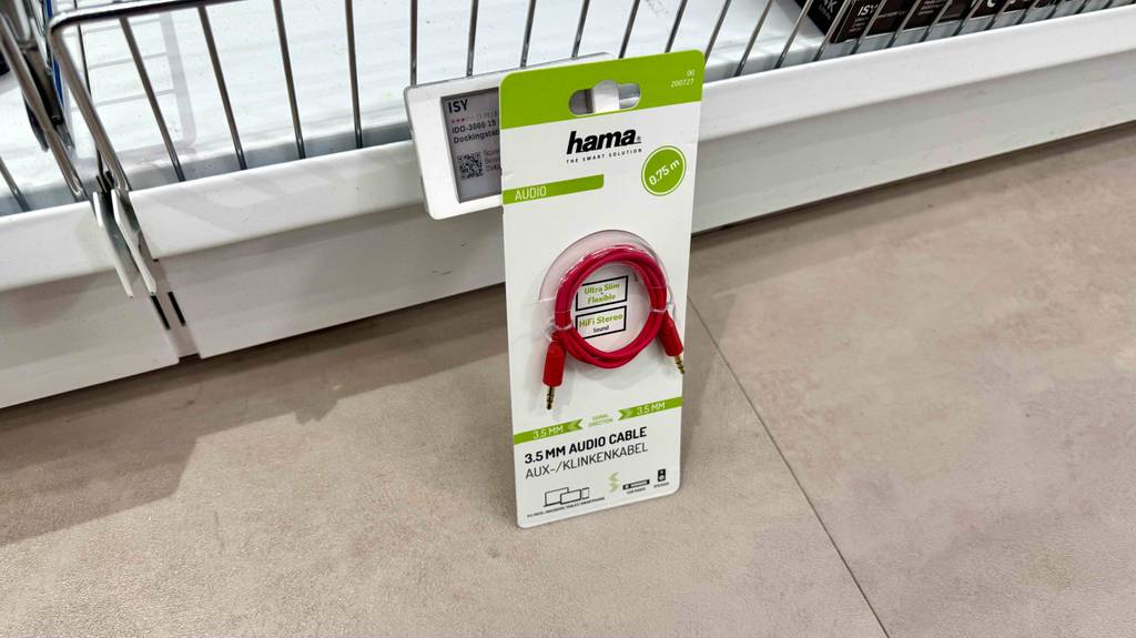 Ein getestetes Aux-Kabel in der Verpackung lehnt vor einem Verkaufsregal.