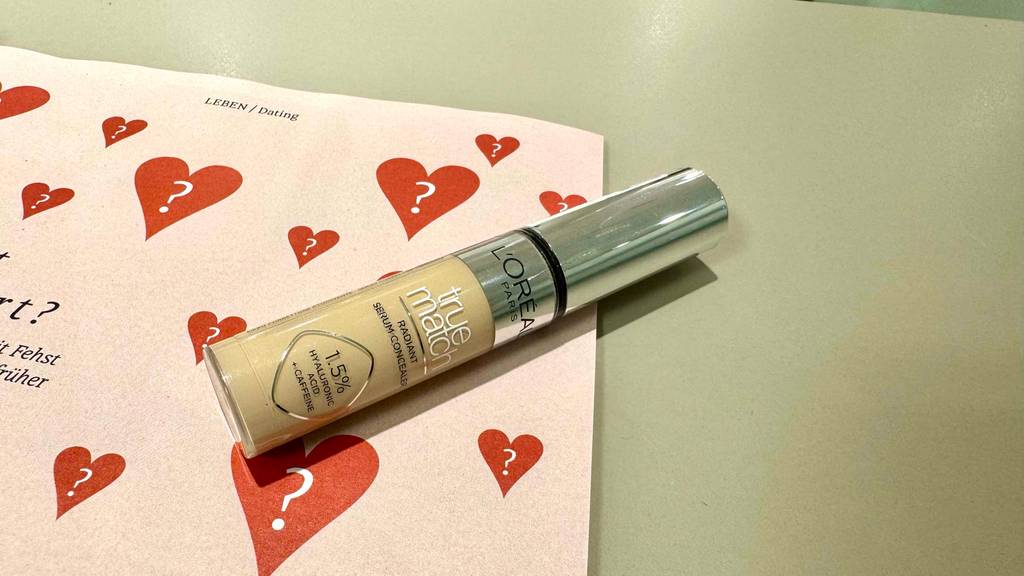 Ein L'Oréal-Concealer im Test liegt auf einem Blatt mit roten Herzen in einem Drogeriemarkt.