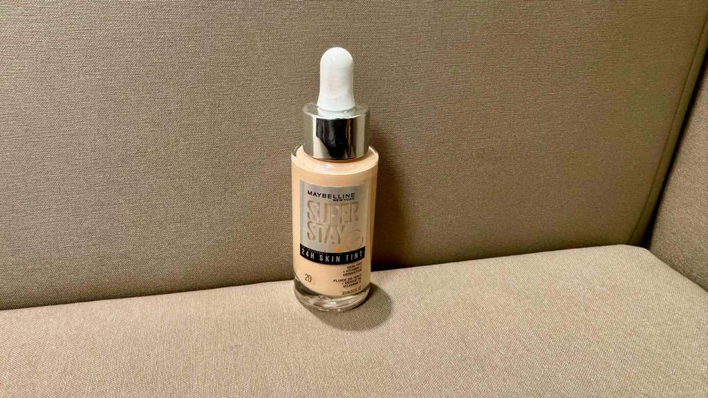 Maybelline-Make-Up-Test: Eine Flasche inklusive Pipette steht auf einem beigefarbenen Sofa.