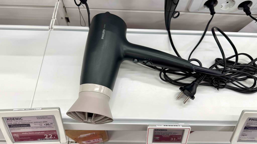 Der getestete Philips-Haartrockner liegt auf einem weißen Regal mit Preisschildern im Verkaufsbereich.