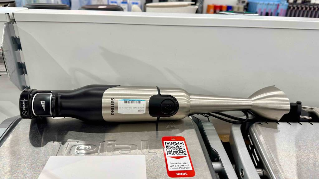 Der Philips-Stabmixer im Test ist in Schwarz mit Edelstahl erhältlich und liegt auf anderen Küchenutensilien auf einem Verkaufsregal.