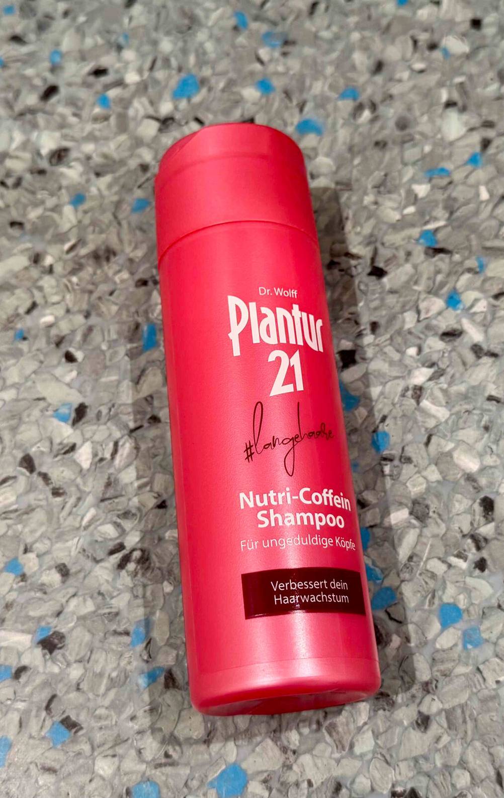 Plantur-Shampoo im Test: Eine rote Kunststoffflasche mit Nutri-Coffein-Shampoo liegt auf dem Boden.
