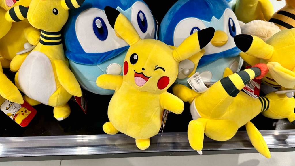 Getestete: Ein gelbes Pokémon-Kuscheltier liegt vor einem Haufen Kuscheltiere im Regal.