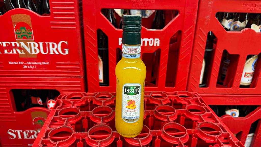 Teisseire-Sirup-Test: Eine Flasche mit gelber Flüssigkeit steht auf einem roten Getränkekasten.