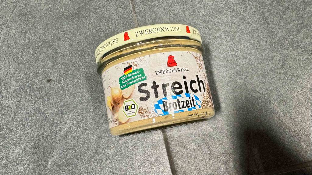 Ein Glas mit getestetem Zwergenwiese Brotaufstrich liegt auf dem Boden.