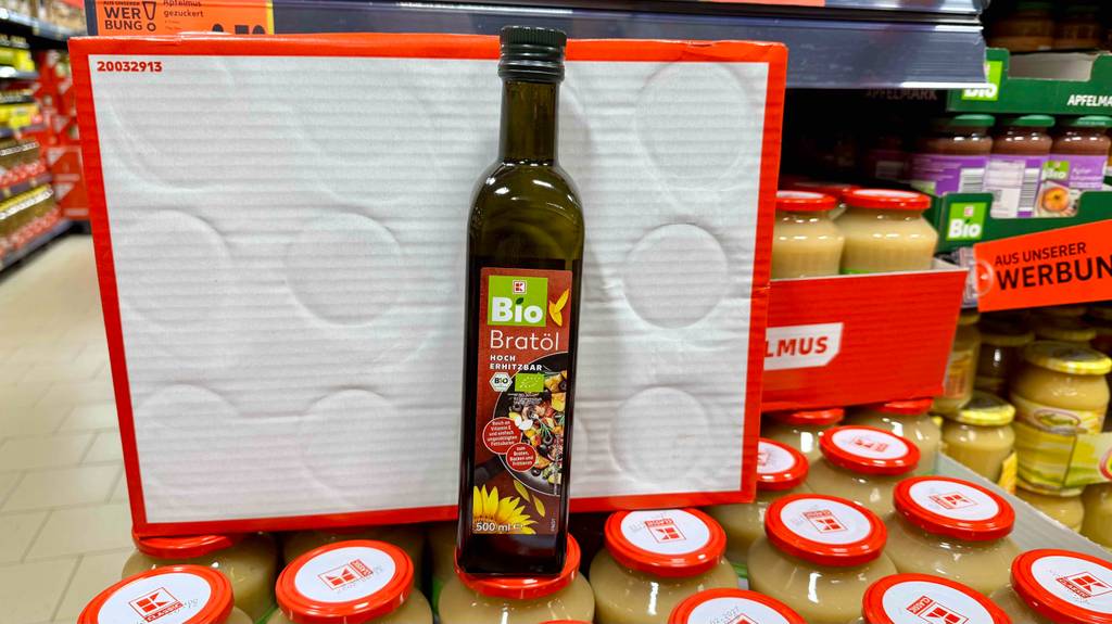 Eine Flasche Bio-Bratöl steht zum testen auf mehreren Gläsern Apfelmus.