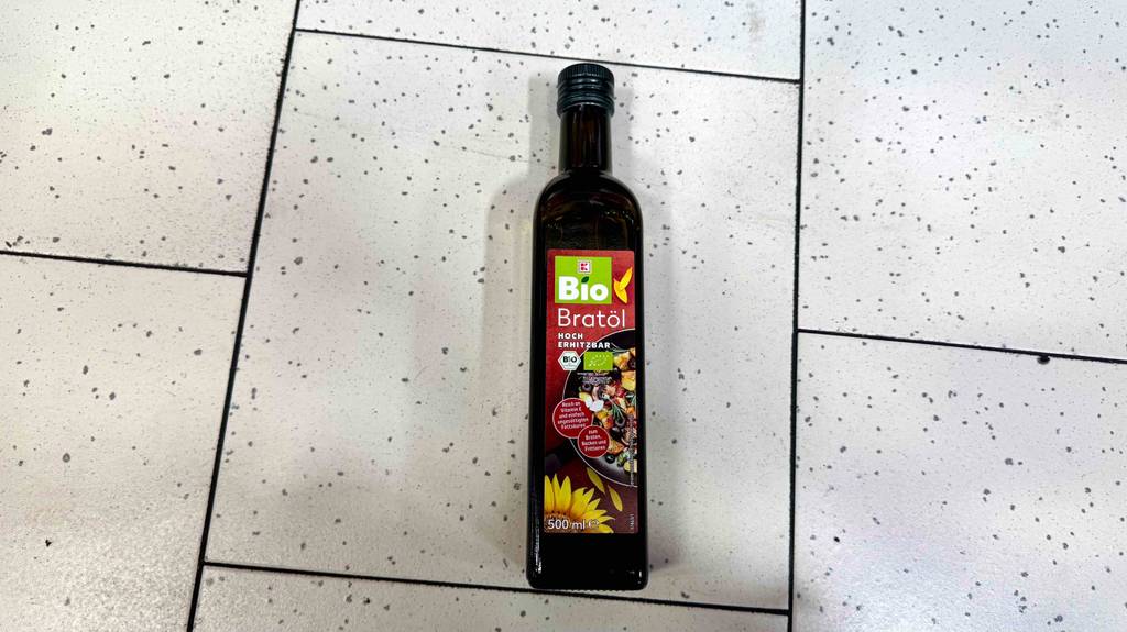 Eine Flasche getestetes Bio-Bratöl liegt auf einem hellen Fliesenboden.
