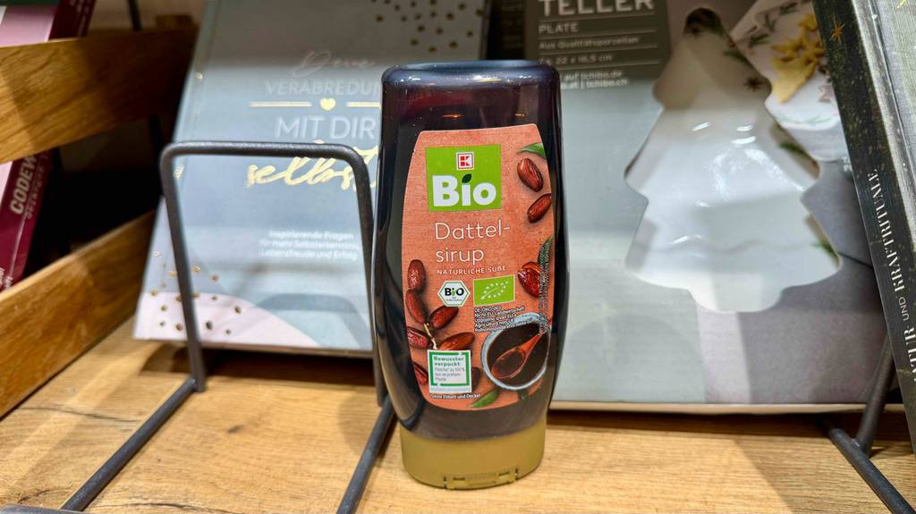 Getestet: Dattelsirup in der Quetschflasche steht vor einem verpackten Teller im Verkaufsbereich.
