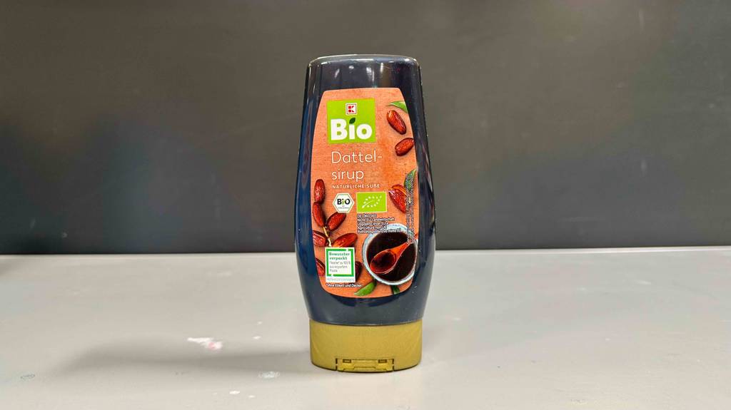 Im Test: Dattelsirup in der Quetschflasche steht vor einer grauen Wand.