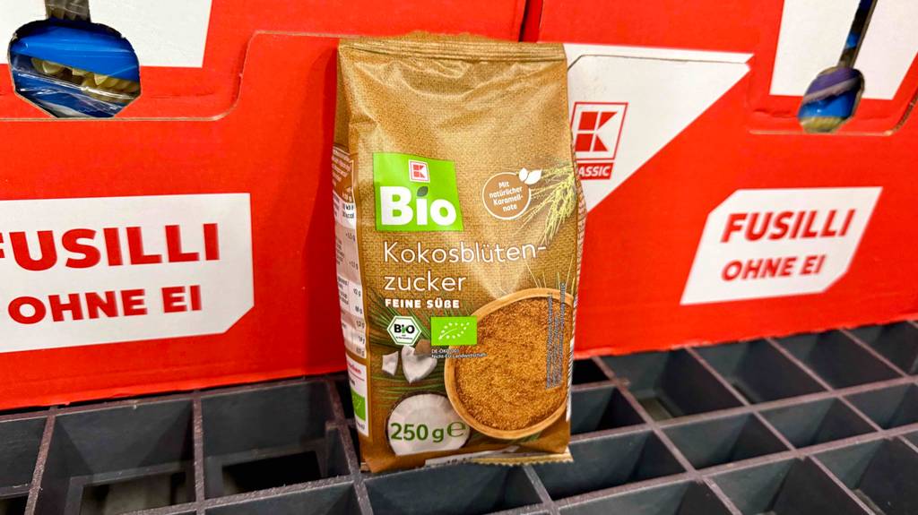 Im Test: Kokosblütenzucker in einer 250-g-Packung steht vor roten Kartons mit Nudeln.