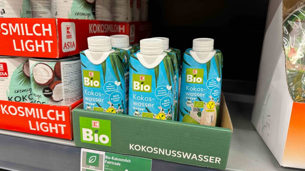 Mehrere Tetrapaks mit getestetem Bio-Kokoswasser stehen in einem Karton auf dem Verkaufsregal.