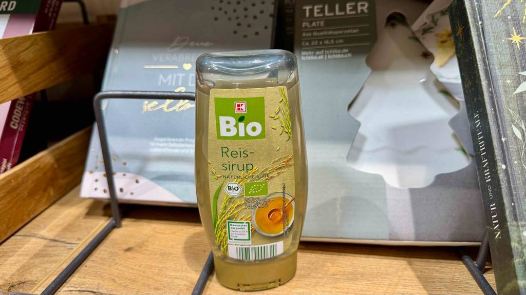 Eine Flasche mit Reissirup steht zum Testen in einem Holzregal.