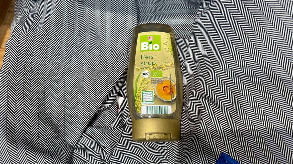 Eine Flasche mit getestetem Reissirup liegt auf einem dunklen Tuch.