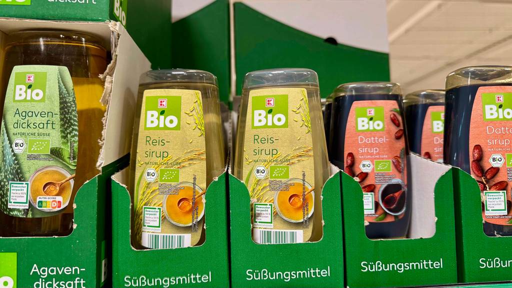 Reissirup im Test: Mehrere Flaschen stehen zwischen anderen Produkten in einem Regal.