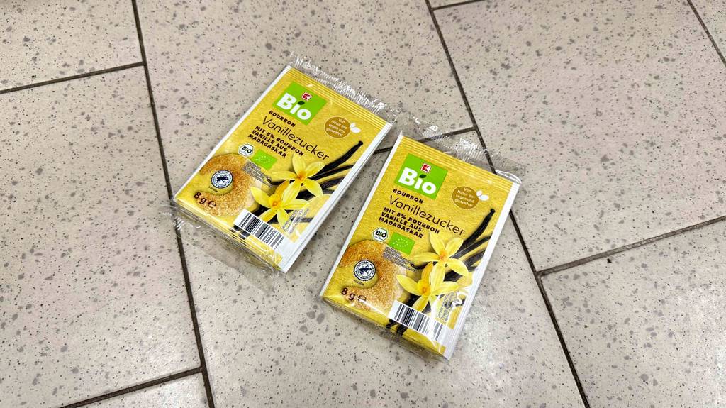 Zwei 8-g-Packungen mit getestetem Vanillezucker der Marke Kaufland liegen auf einem Fliesenboden.