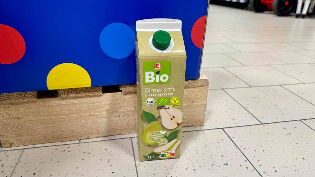 Eine Tetrapak mit getestetem Birnensaft steht vor einer Palette auf dem Boden.