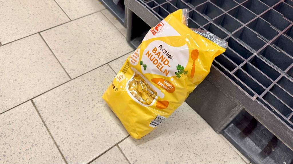 Auf dem Fliesenbelag liegen Bandnudeln im Test in einer gelben 500-g-Packung.