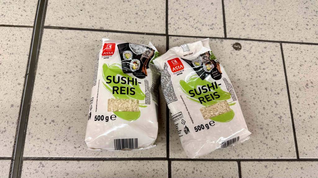 Zwei 500-g-Packungen mit Sichtfenstern inklusive Sushi-Reis im Test liegen auf einem Fliesenbelag.