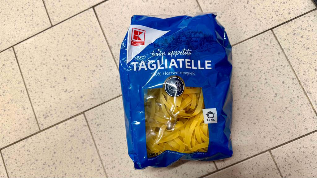Tagliatelle im Test: Eine Packung getrockneter Nudeln liegt auf einem Fliesenbelag.