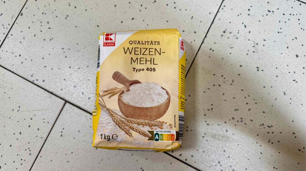 Getestetes Weizenmehl von Kaufland in einer 1-kg-Packung liegt auf einem Fliesenbelag.