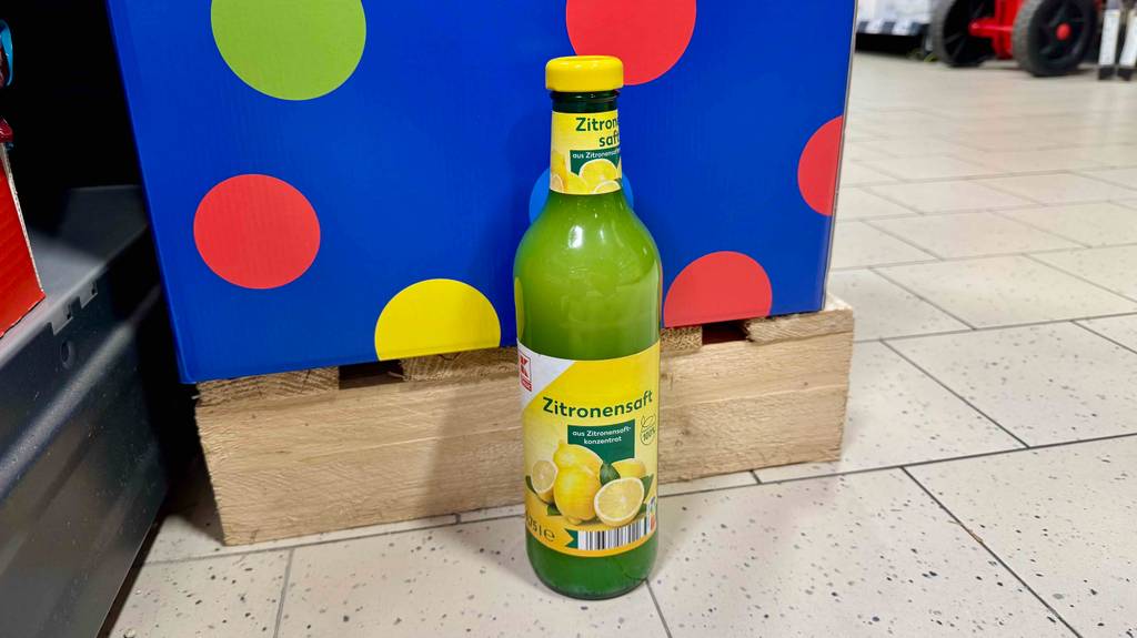 Eine 750-ml-Glasflasche mit Zitronensaft im Test steht in einem Supermarkt auf dem Boden.
