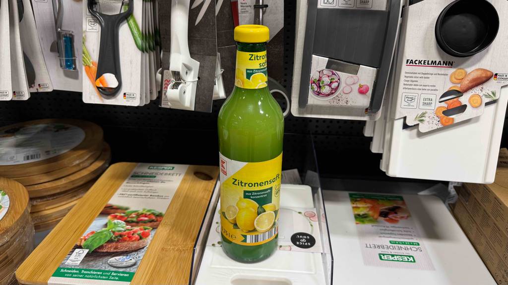 Eine 750-ml-Glasflasche mit getestetem Zitronensaft steht in einem Supermarkt auf einem Regal mit Küchenutensilien.