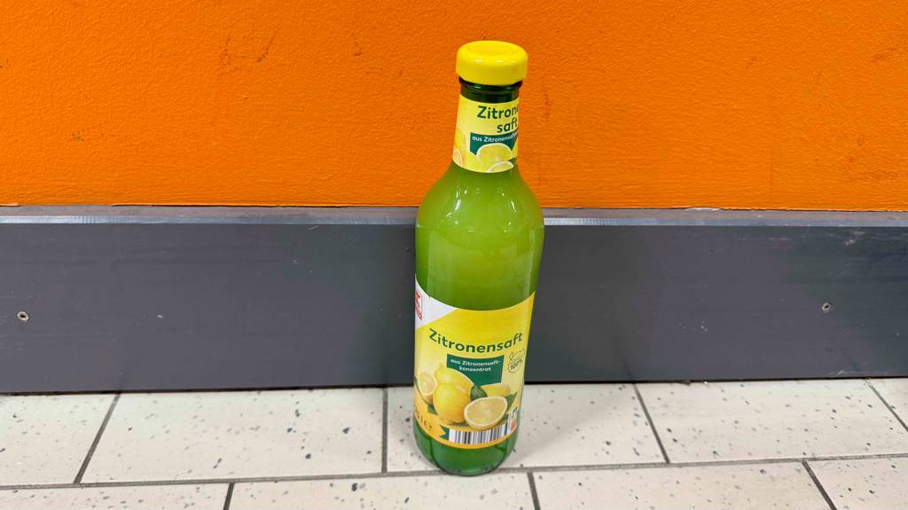 Im Test: Der Zitronensaft in der Glasflasche steht vor einem Regal im Supermarkt auf dem Boden.