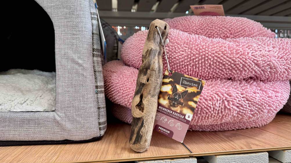 Ein getestetes Kauholz Hund vor rosa Hundebetten in einem Verkaufsregal.