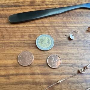 Münzen, Schmuck und Messer auf einem braunen Holztisch