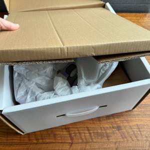 Eine Hand entfernt einen Karton aus der Verpackung des Kela Calido
