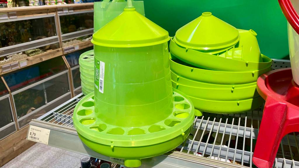 Futterautomaten für Hühner im Test: Ansicht von schräg oben auf ein giftgrünes Modell inklusive Aussparungen für die Futteraufnahme, das in einem Verkaufsbereich für Tier-Zubehör steht.