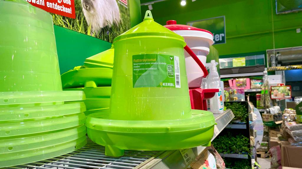Futterautomat für Hühner im Test: Seitenansicht auf ein giftgrünes Modell von Kerbel auf einem Verkaufsregal mit weiteren Utensilien für Tiere.