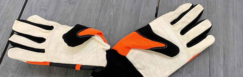 Ein Paar getestete Arbeitshandschuhe liegen mit Fokus auf ihre weiße Leder-Handinnenfläche auf einem hellgrauen Untergrund.