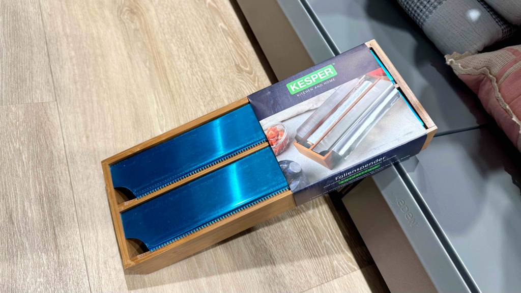Im Test: Ein Folienspender lehnt quer über einem Laminatboden an ein Regal.