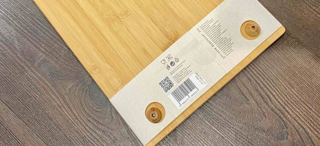 Eine getestete Herdabdeckplatte aus Holz mit angeschraubten Standfüßen liegt auf einer Holzoberfläche.