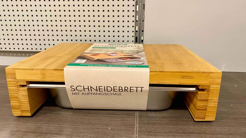 Getestetes Schneidebrett mit Auffangschale steht auf einem Untergrund aus Holz.