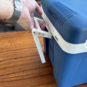 Eine Hand hält einen Griff der Kesser-Kühlbox mit Rädern fest.