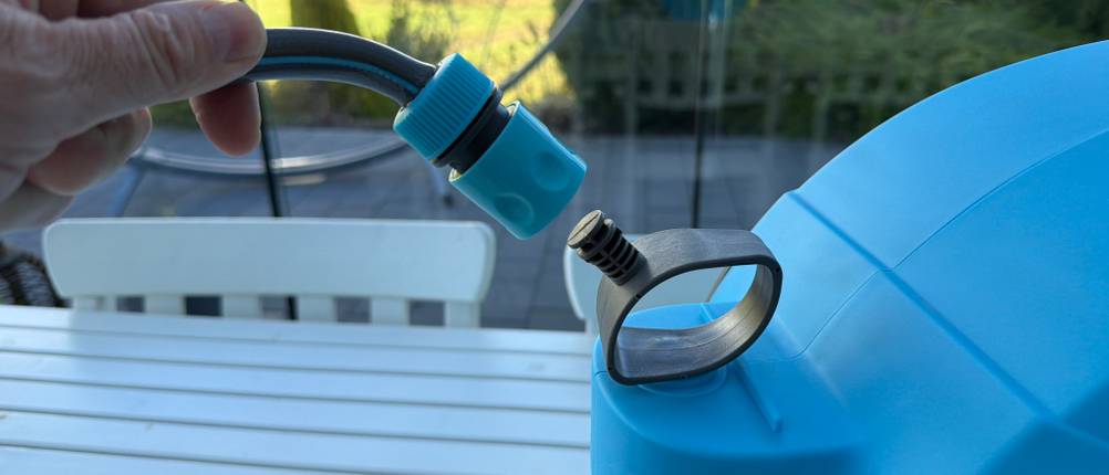 Eine Hand befestigt den Schlauch an der Halterung der Kesser-Schlauchtrommel