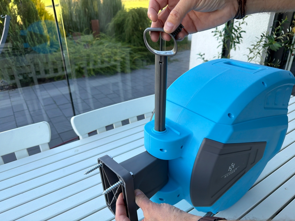 Eine Hand befestigt die Wandhalterung an der Kesser-Schlauchtrommel