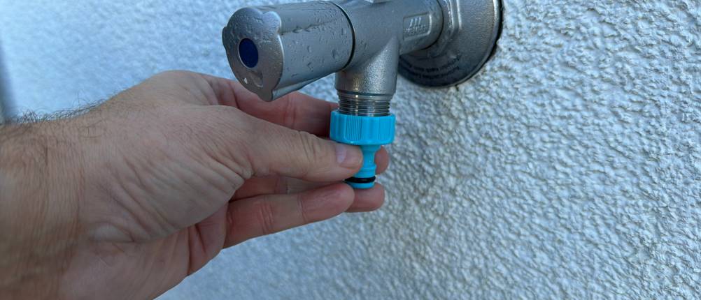 Eine Hand schraubt einen Anschluss der Kesser-Schlauchtrommel auf einen Wasseranschluss