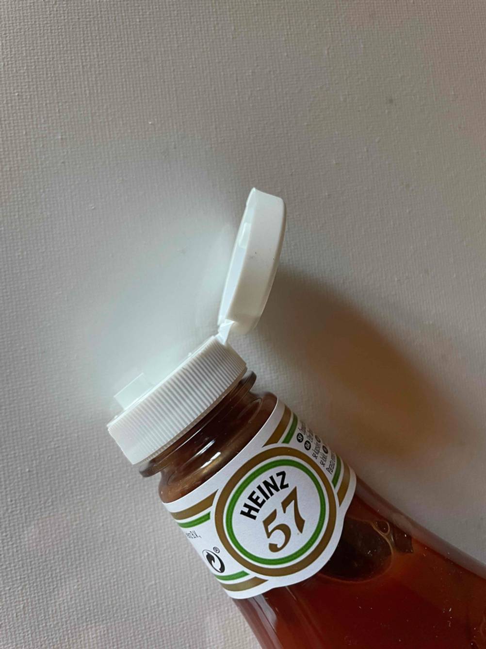 Nahaufnahme des geöffneten Verschlusses einer Flasche Ketchup im Test auf einer hellen Fläche.