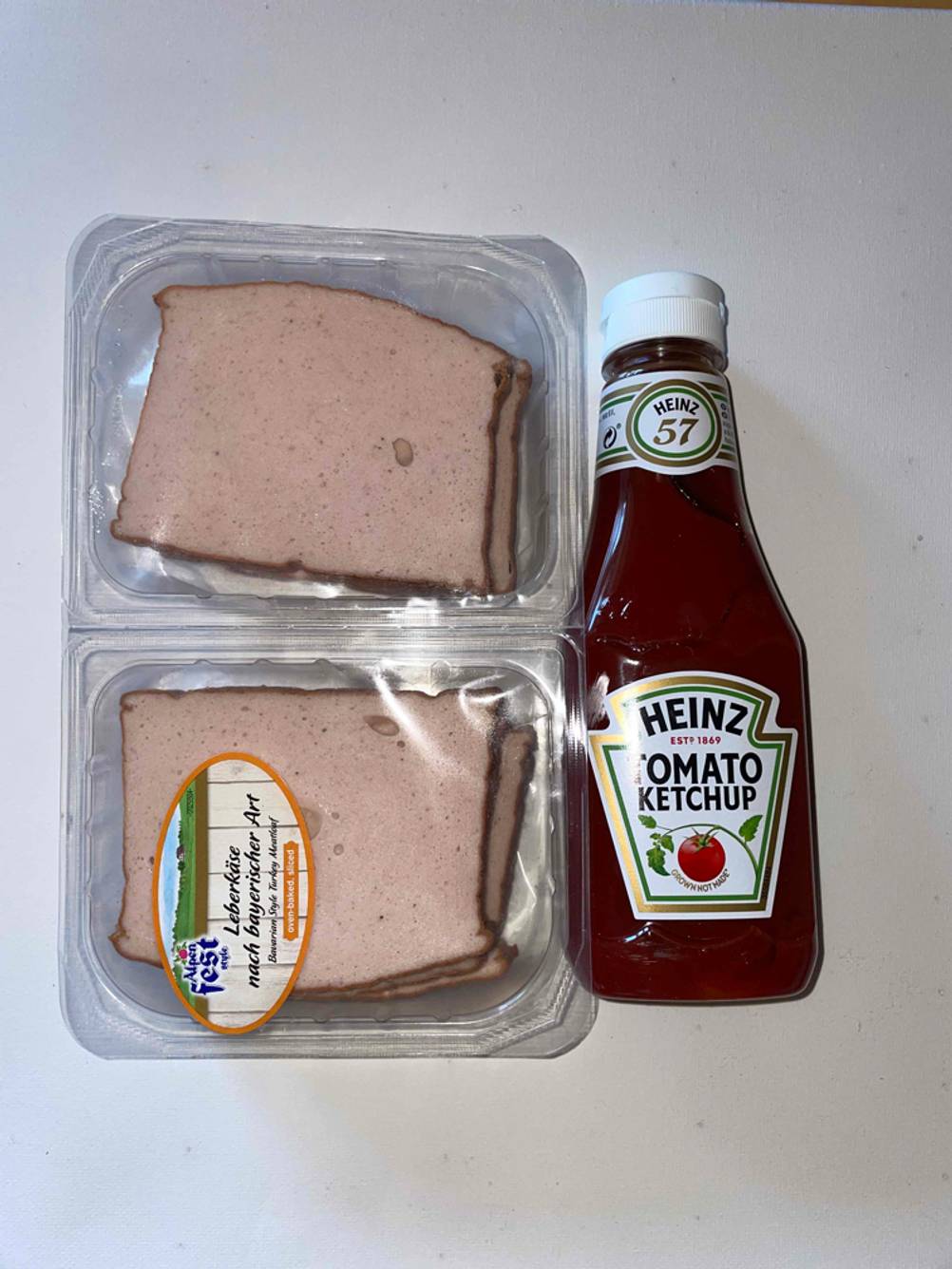 Leberkäse liegt neben einer getesteten Ketchup-Packung. 