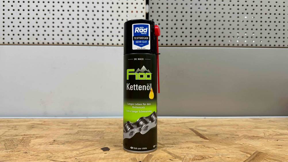 Auf einer Holzfläche vor einer grauen Wand steht eine Dose des getesteten Kettenöls.