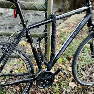 Ein Fahrrad ist mit dem Kettenschloss von Abus an einen Zaun angeschlossen.