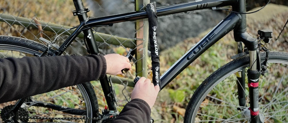 Ein Fahrrad wird mit dem Kettenschloss von Dunlop an einen Zaun angeschlossen.
