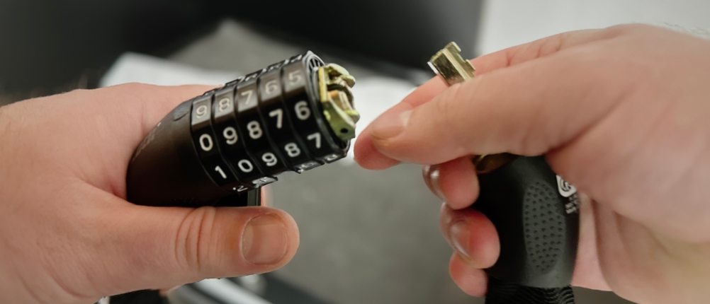 Das geöffnete Kettenschloss von Dunlop mit Zahlenschloss wird in der Hand gehalten.