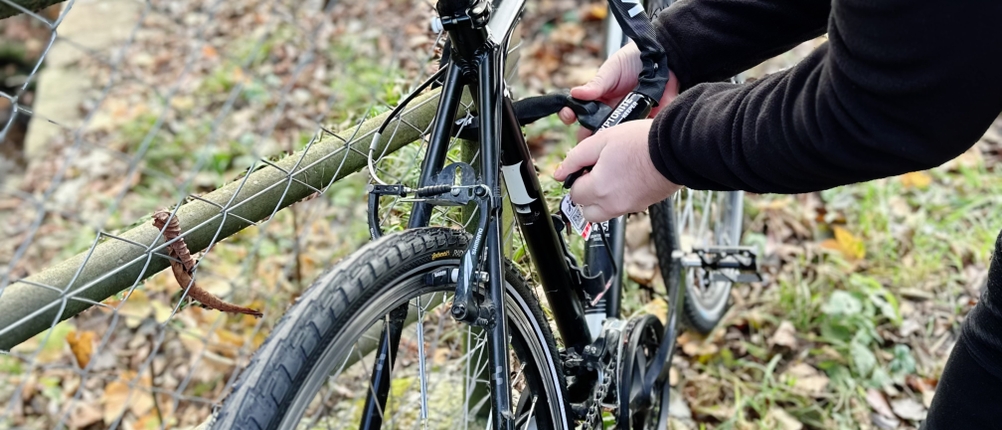 Ein Fahrrad wird mit dem Kettenschloss von Kryptonite an einen Zaun angeschlossen.