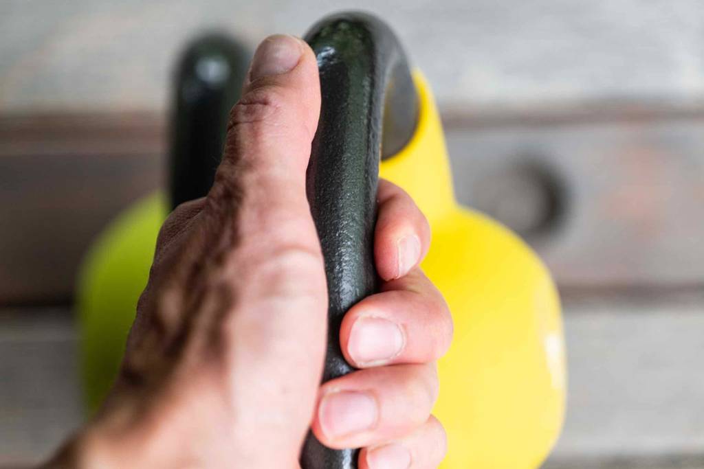 Zwei Kettlebells im Test: Eine Hand greift ein 8-kg schweres Kettlebell.