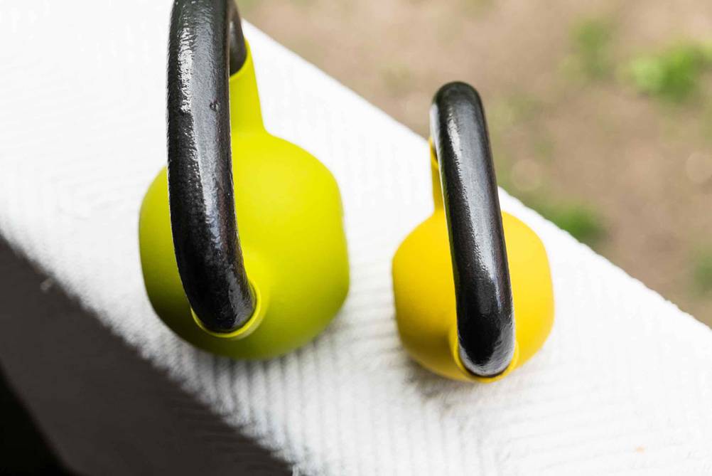 Getestet: Eine grüne und eine gelbe Kettlebell von oben mit schwarzen Griffen.