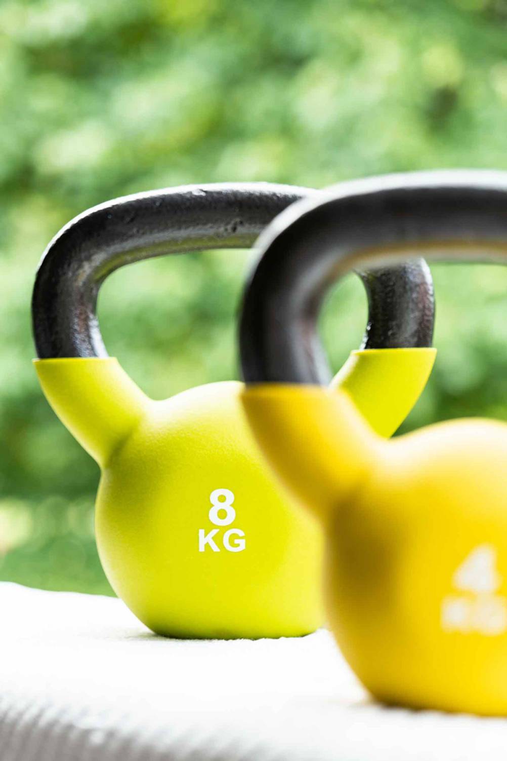 Zwei verschiedenschwere Kettlebells im Test befinden sich im Garten. 